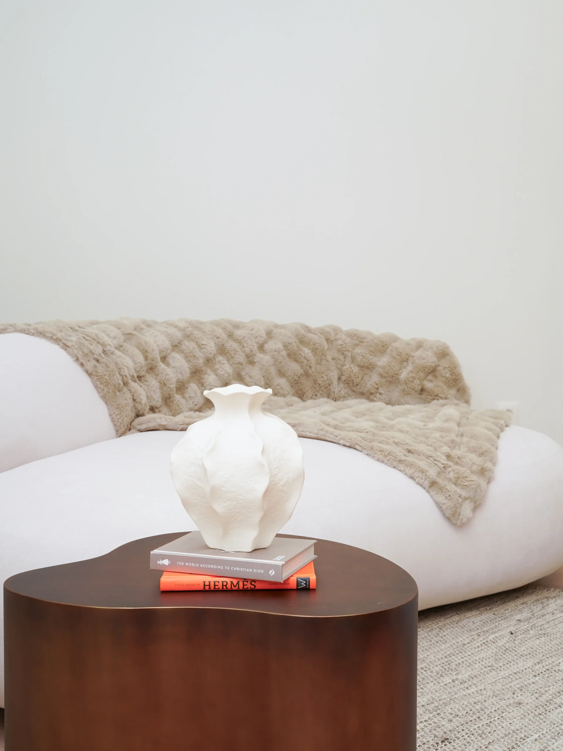 Decorative white vase on wooden side table with sofa and blanket in Antwerp studio markdown Code kopiëren