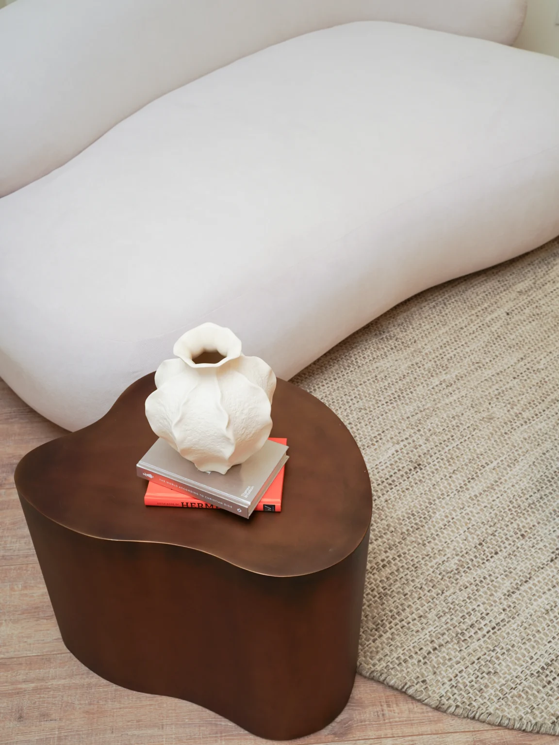 Close-up of white ceramic vase on side table with sofa and rug in Antwerp studio