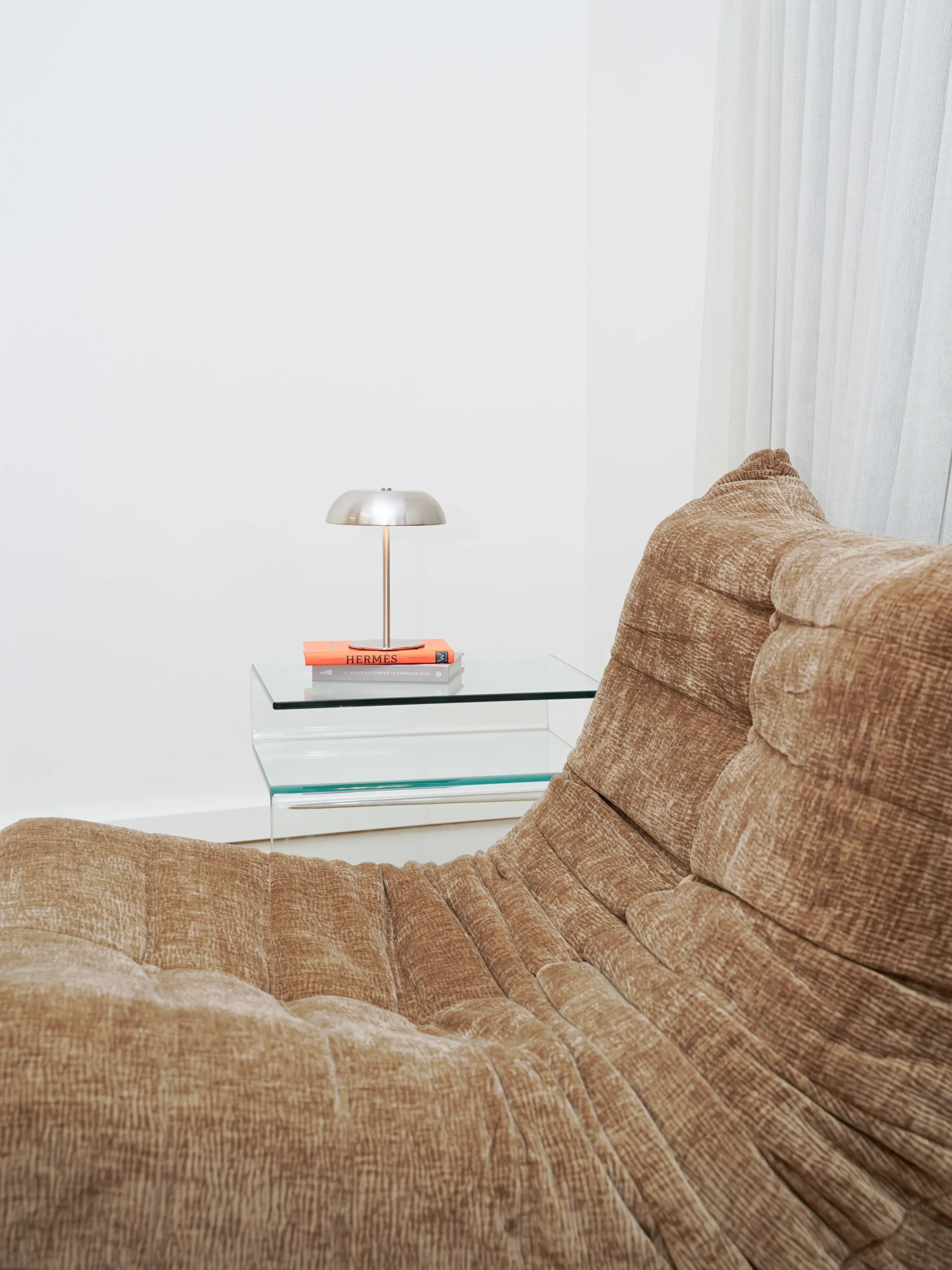 Brown lounge chair with lamp and glass side table in soft lighting at Antwerp studio