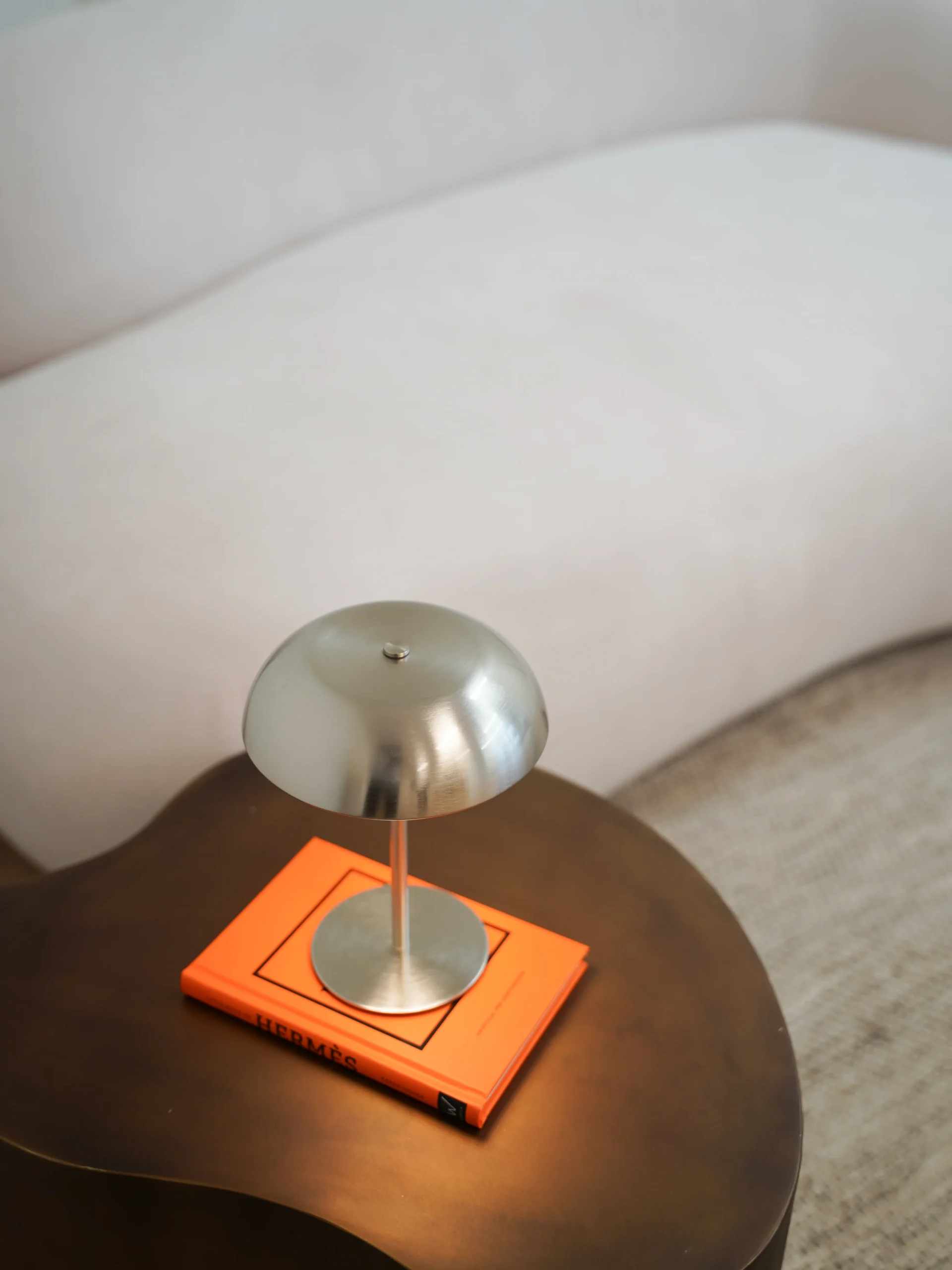 Silver lamp on side table with Hermès book and white sofa in Antwerp studio