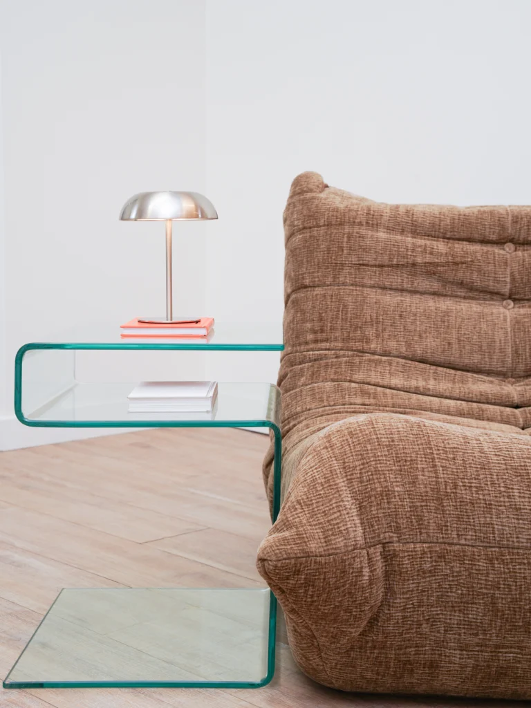 Close-up of brown lounge chair with glass table and silver lamp in Antwerp studio