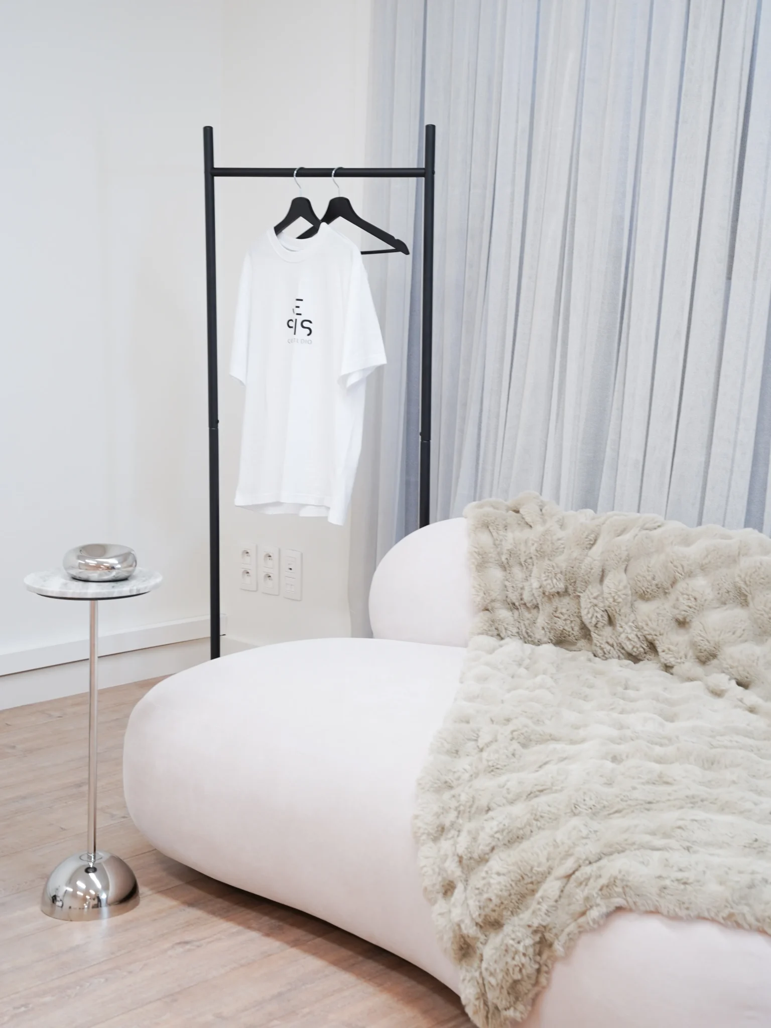 Studio sofa with fur blanket and Je Suis Content Studio branded t-shirt on clothing rack
