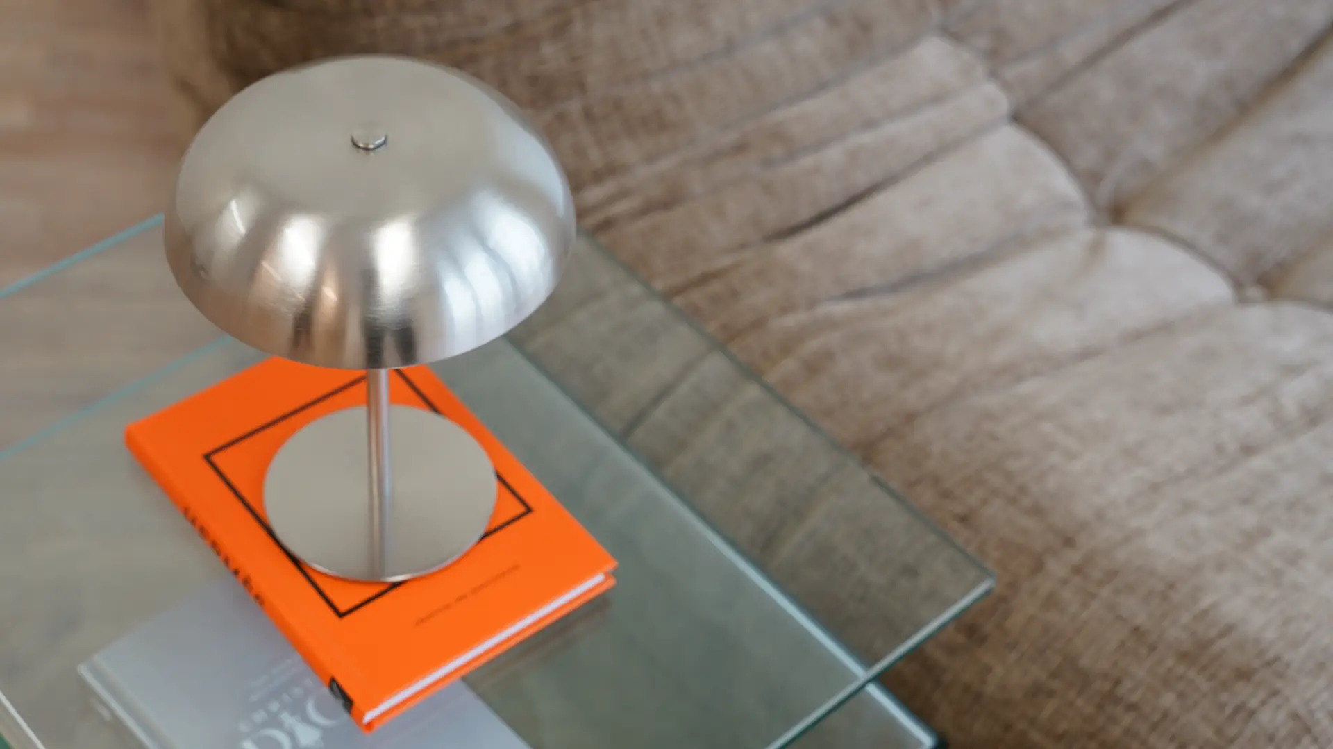 Close-up of modern silver lamp on orange book with glass table in Antwerp studio