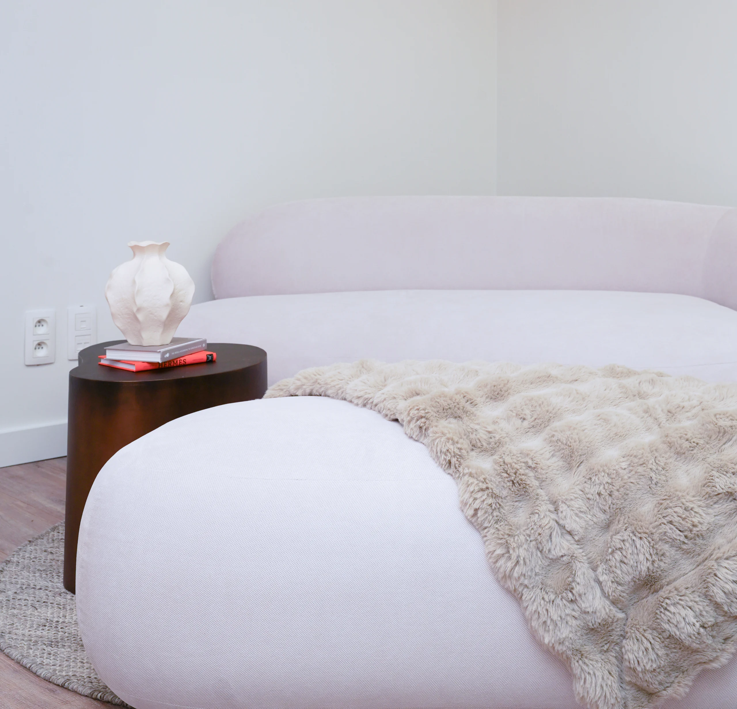 Modern studio interiorCozy studio lounge with soft sofa, beige fur blanket, and modern side table in Antwerp Deurne with white sofa, fur blanket, and wooden side table in Antwerp Deurne