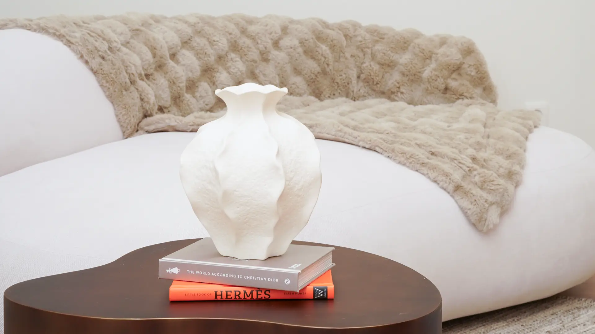 Close-up of modern silver lamp on orange book with glass table in Antwerp studio